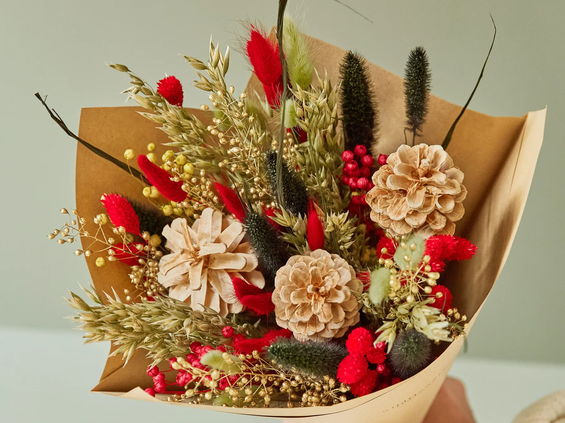Holiday Cheer classic dried bouquet with red phalaris, pinecone flowers, and berries in a kraft wrap