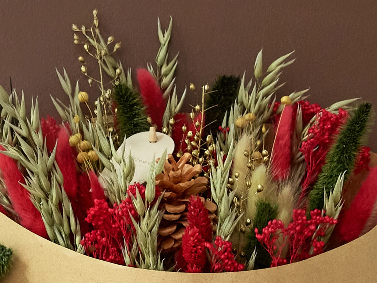 Holiday Cheer dried field bouquet with red bunny tails, red flowers, oats, and a pinecone in a kraft wrap