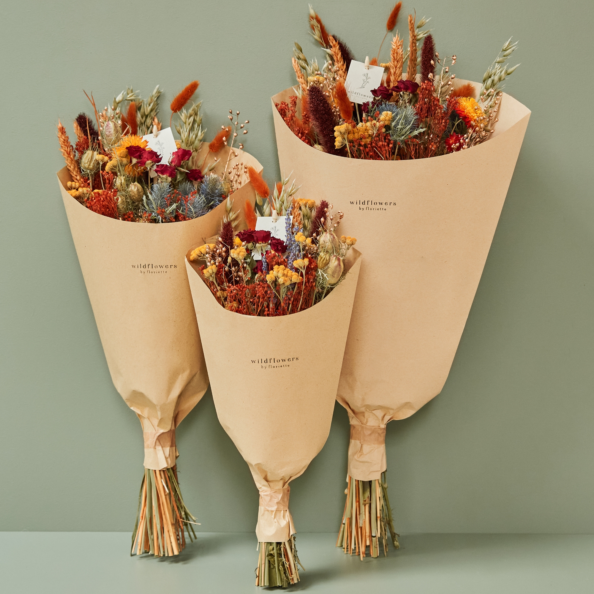 Three field bouquets in kraft paper wraps